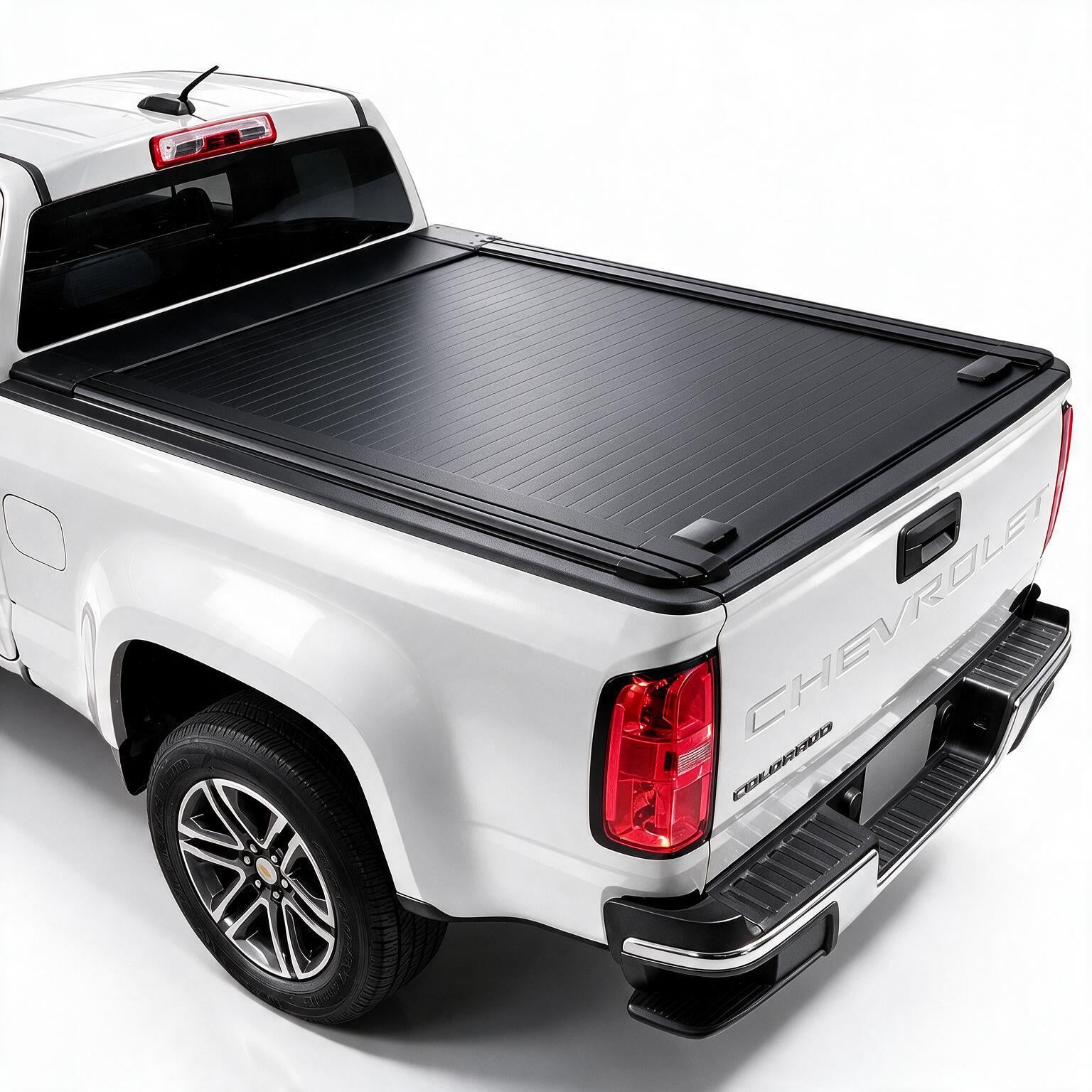 A black retractable truck bed cover installed on the bed of a white Chevrolet pickup truck, shown from a rear three-quarter angle against a plain white background.