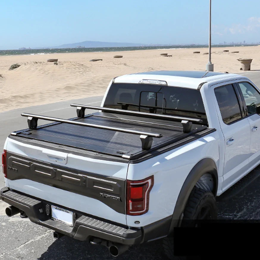 White truck with a tonneau cover and roof rack in an open area