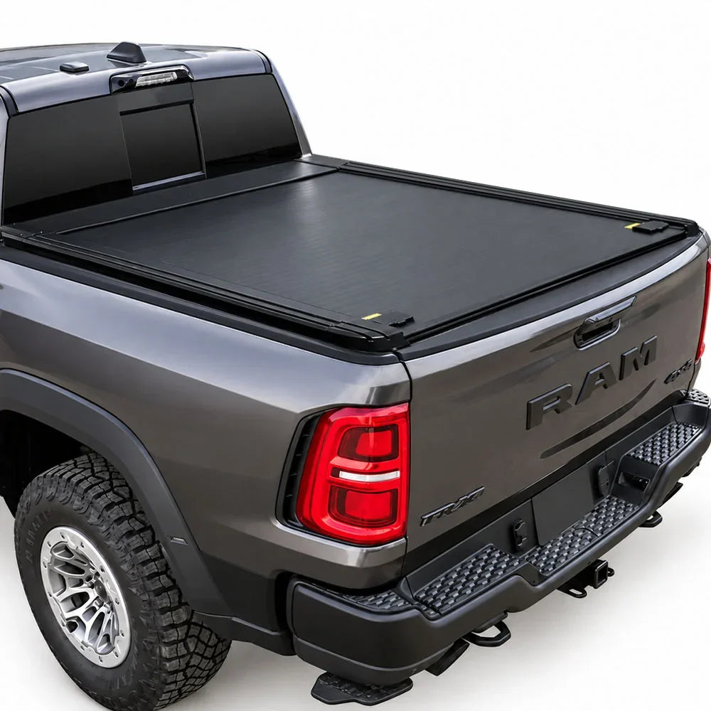 A black roll-up truck bed cover installed on the bed of a dark gray Ram pickup truck, shown from a rear three-quarter angle against a white studio background.