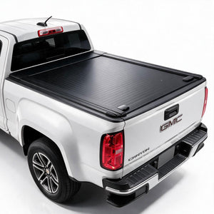 A black roll-up truck bed cover installed on the bed of a white GMC Canyon pickup truck, shown from a rear three-quarter angle on a white studio background.