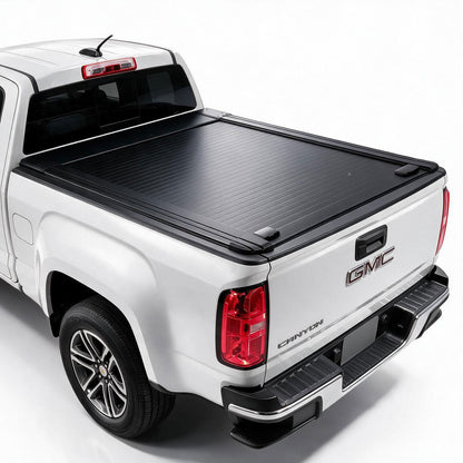 A black roll-up truck bed cover installed on the bed of a white GMC Canyon pickup truck, shown from a rear three-quarter angle on a white studio background.