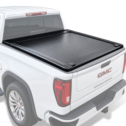 A black truck bed cover installed on the bed of a white GMC Sierra pickup truck, shown from a rear three-quarter angle against a clean white background.