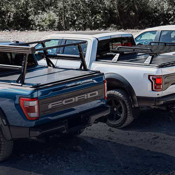 Two Ford trucks parked side by side with a forest in the background