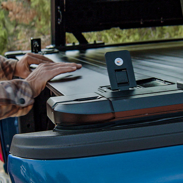 Person interacting with a device on the back of a blue truck