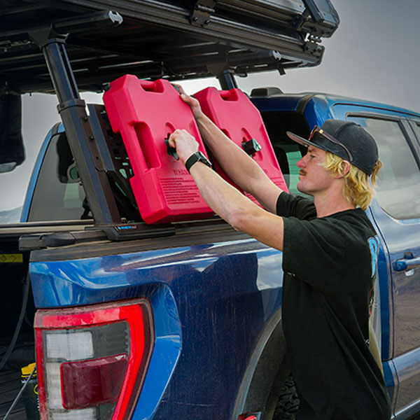Person loading a red GAS TANK onto the back of a blue truck