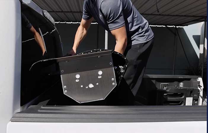 Person loading a tonneau cover canister into the back of a truck