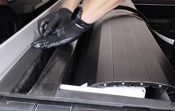 Person wearing black gloves cleaning a bulkhead area.