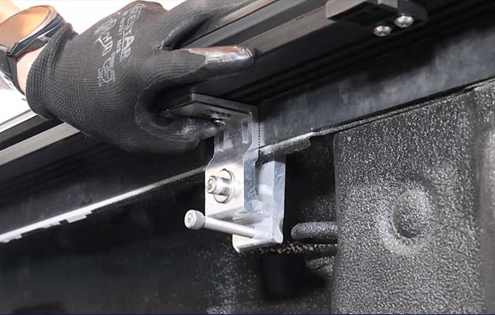 Hand wearing a black glove using a tool on a metal surface