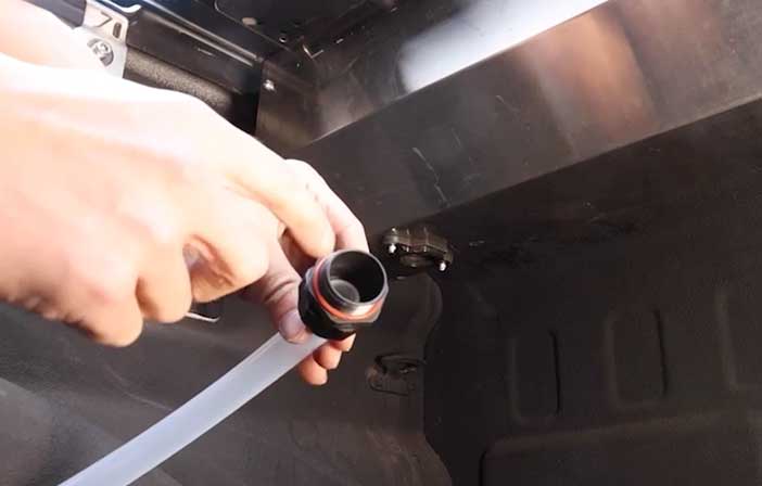 Person showing a drain tube to attach on a canister