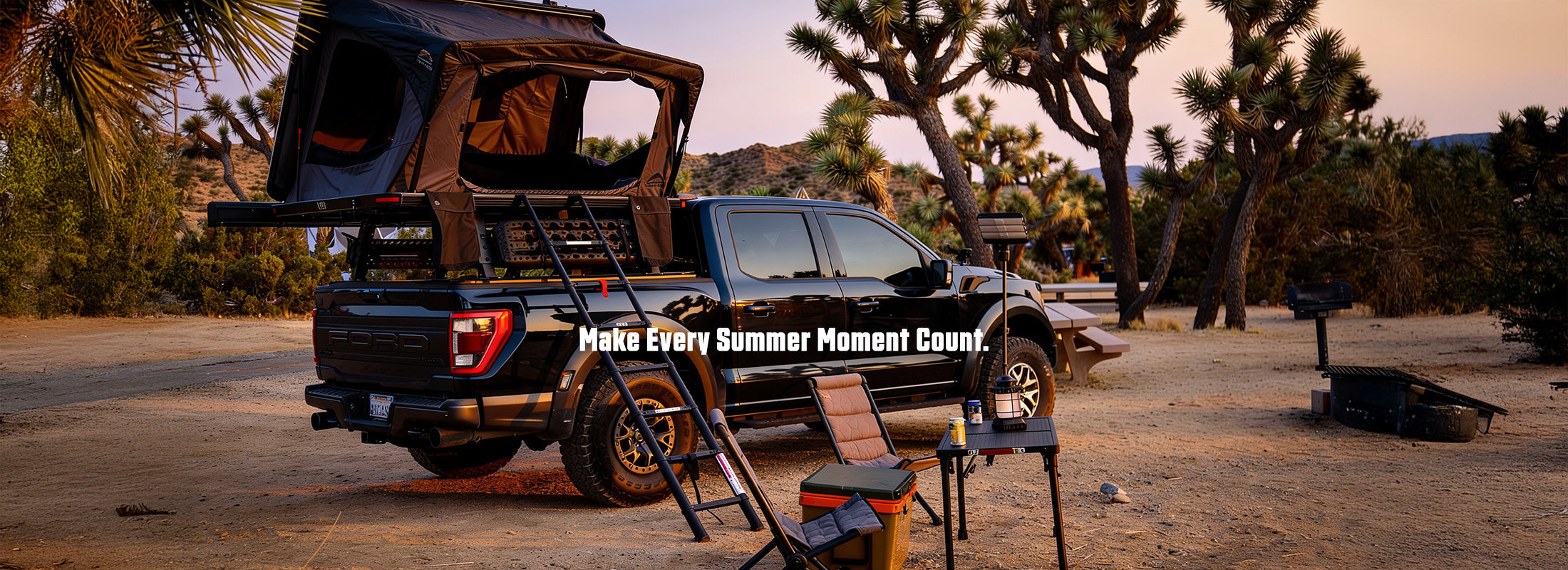 A black pickup truck with a rooftop tent and ladder setup parked outdoors in a desert campsite at sunset, with chairs, a cooler, and trees in the background. White text across the center reads 'Make Every Summer Moment Count.