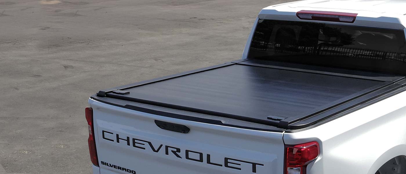 Chevrolet Silverado truck bed with a black tonneau cover on a concrete surface