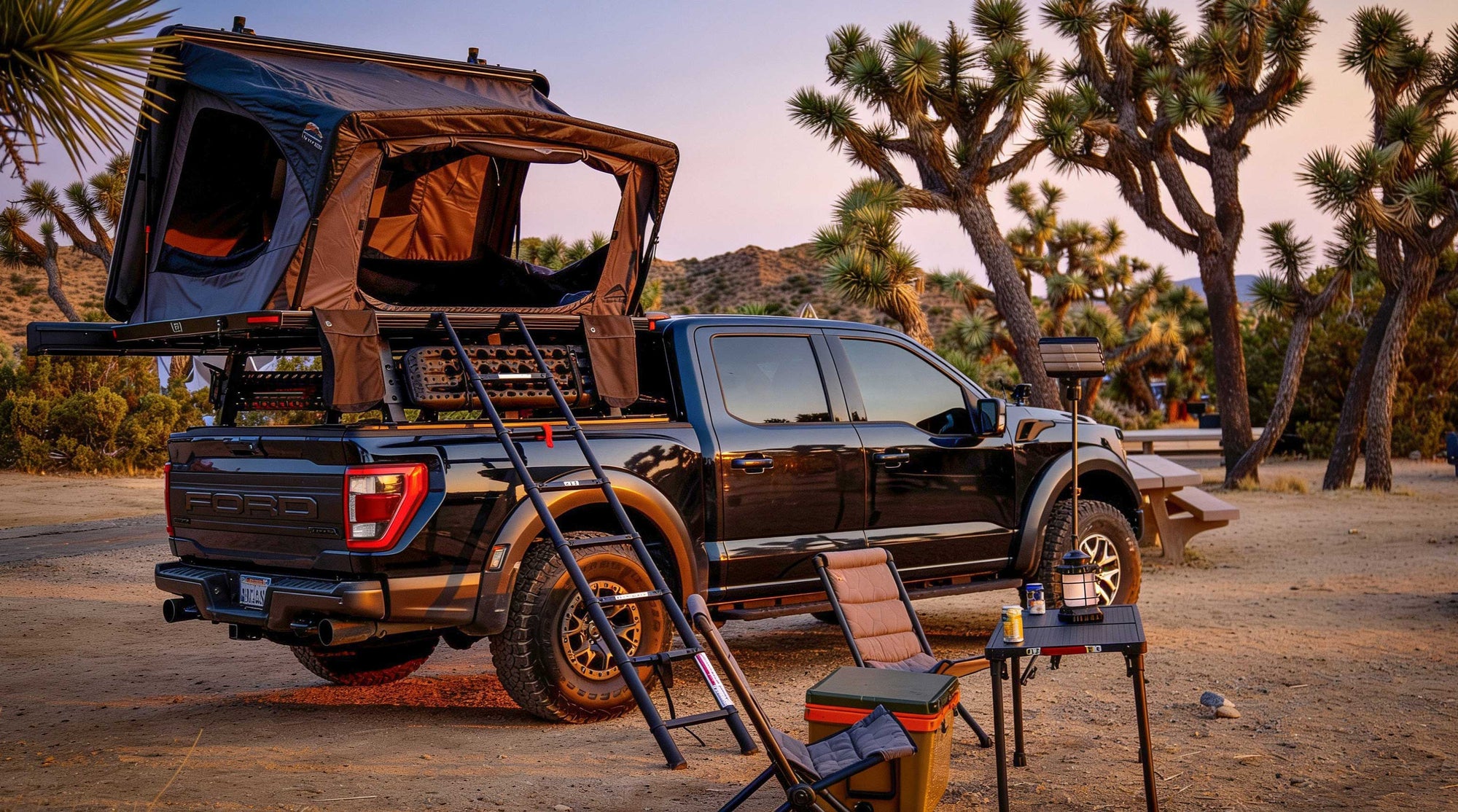 Blue truck with a rooftop tent in a desert setting with Joshua trees.